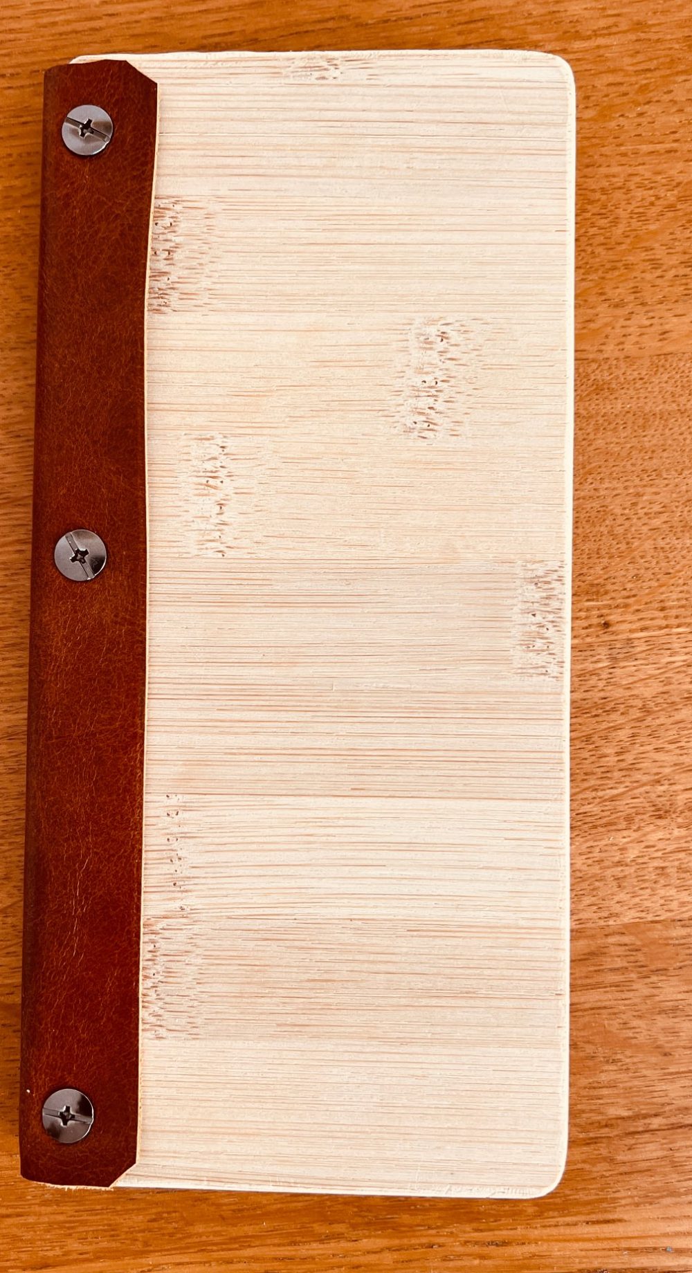Closed bamboo bill presenter with a brown leather spine and three screws
